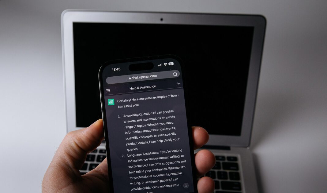 Smartphone con la aplicación de ChatGPT frente a una notebook